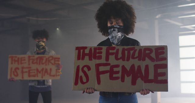 Women activists show support for gender equality by holding signs that read 'The future is female.' This can be used for gender equality campaigns, feminist causes, or social justice projects.