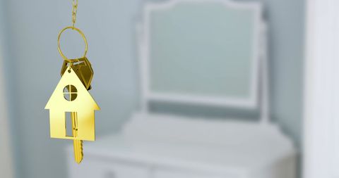Golden house keychain over blurred white background