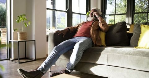 Senior man relaxing on sofa while speaking on smartphone