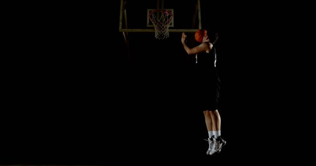 Basketball Player Dunking Basketball in Dark Arena - Download Free Stock Photos Pikwizard.com