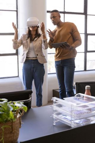 Diverse coworkers testing virtual reality headset while collaborating with tablet
