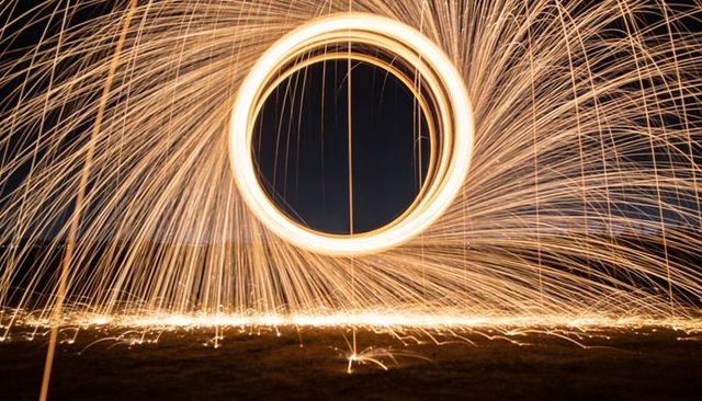 Spinning steel wool sparks creating circular light halo and dynamic night trails