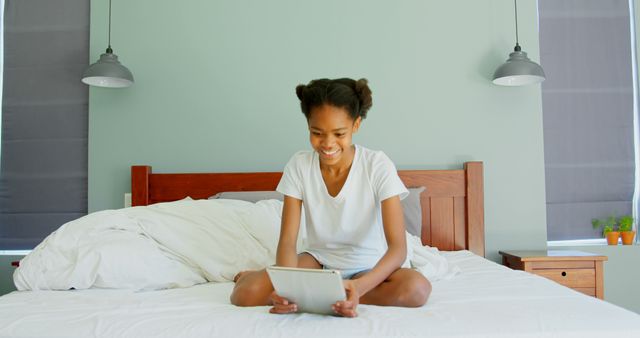 Young African American Girl Enjoying Tablet on Bed in Modern Bedroom - Download Free Stock Images Pikwizard.com