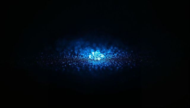 Shimmering blue droplet cluster in dark minimalistic studio