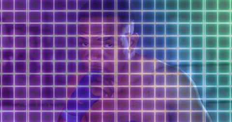 Shirtless boxer standing guard with blue hand wraps in neon holographic grid studio