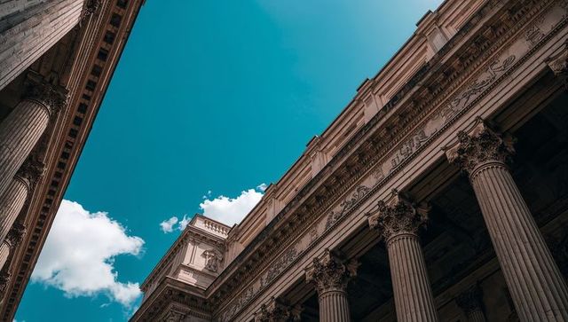 Rising neoclassical facade with corinthian capitals and fluted columns against blue sky