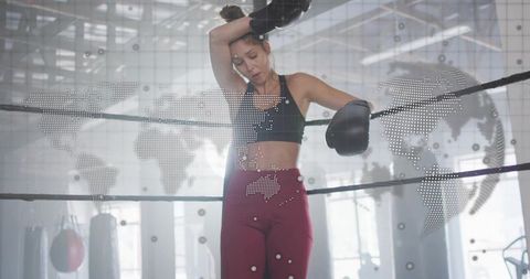 Female boxer leaning on ring ropes after intense workout with global network overlay