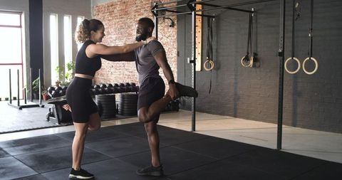 Fitness Partners Stretching Quads in Modern Gym Environment