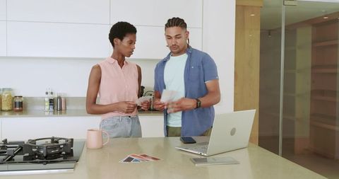 Diverse couple comparing paint swatches in modern kitchen