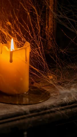 Flickering Pillar Candle Melting Wax and Dust Drifting on Rustic Tabletop Vertical Video