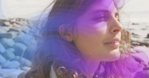 Young Woman Standing on Rocky Shore in Serene Coastal Scene