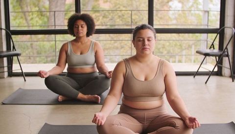 Plus-Size Women Meditating Together in Bright Yoga Studio Practicing Mindfulness for Wellbeing