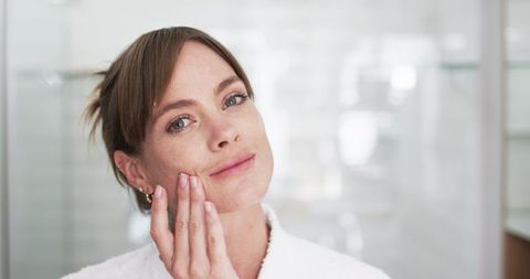 Middle-Aged Woman Enjoying Daily Skincare Routine in Bright Bathroom