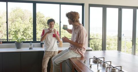 Happy LGBTQ+ Couple Enjoying Coffee in Sunlit Modern Kitchen