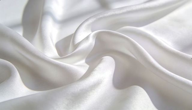 Shimmering white satin draping with glossy folds and smooth silk texture