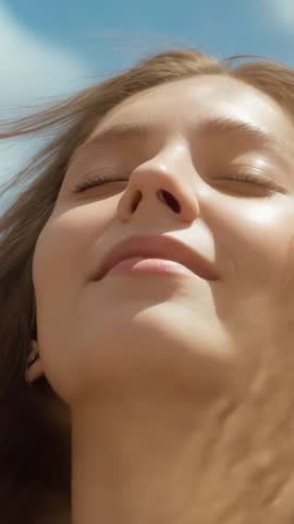 Young woman closing eyes welcoming breeze in open field vertical video