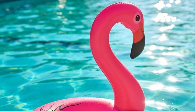 Vibrant pink flamingo pool float floating on turquoise water with sparkling sun reflections