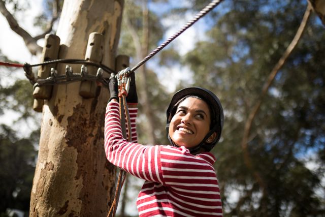 Smiling woman ready to zip line in adventure park on a sunny day