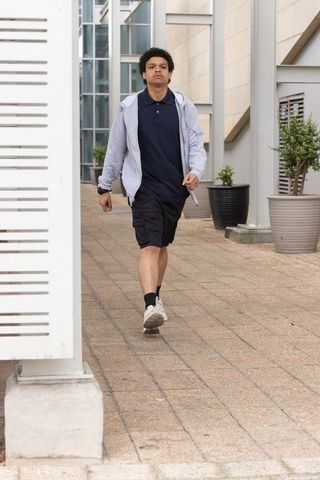 African man walking through modern urban courtyard passing louvered screen and planters