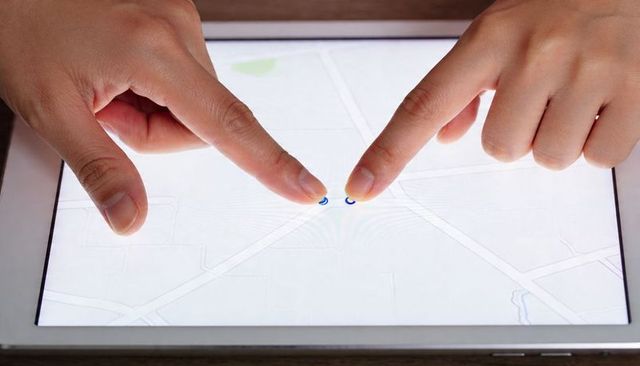 Fingers Pinching to Zoom Map on Tablet Touchscreen with Blue Location Markers