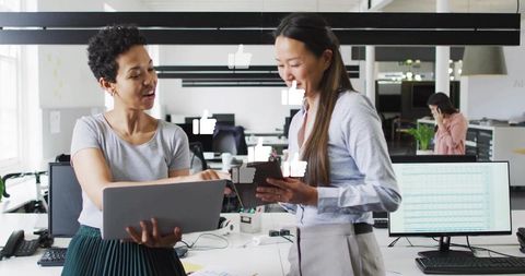 Colleagues collaborating with laptop and tablet in modern open-plan office with social likes