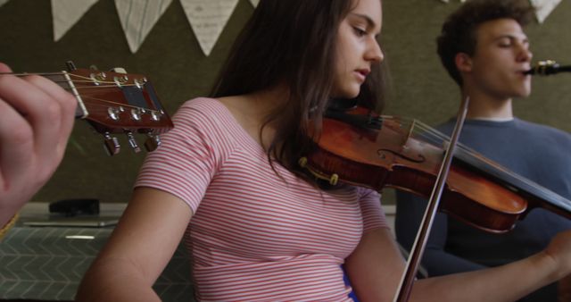 Focused caucasian teenage girl playing violin with friends at school band practice. Music, school, learning, practicing, adolescence, childhood, summer and education, unaltered.