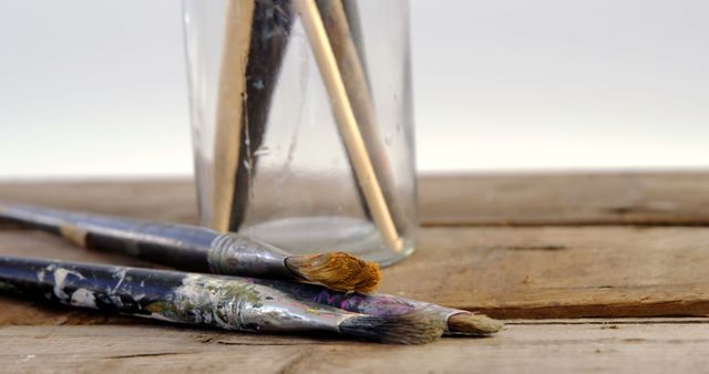 Close-Up of Paintbrushes and Jar on Wooden Table - Download Free Stock Images Pikwizard.com