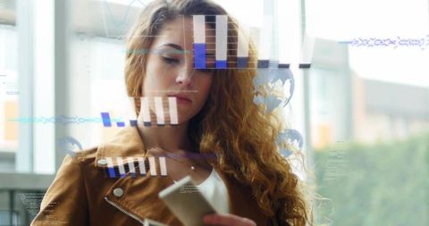 Businesswoman analyzing augmented data on smartphone through glass interface in modern lobby
