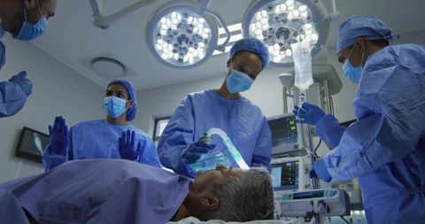 Surgical team administering anesthesia and monitoring patient in operating room