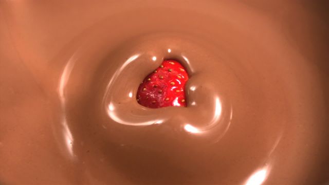 Close-up shot of a strawberry falling into melted chocolate. Excellent for illustrating concepts of indulgence, dessert recipes, food advertisements, and cookbooks. Ideal for use in social media, blog posts, and culinary publications.