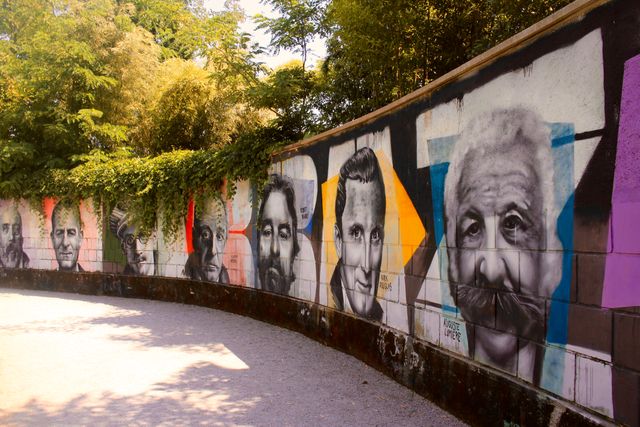 Colorful graffiti wall features vibrant portraits of famous figures in an outdoor park. Perfect for concepts of urban culture, creativity, public art, and youth expression. Ideal for blog posts, travel magazines, urban art showcases, and educational materials on contemporary art.