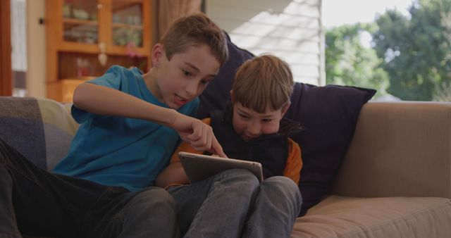 Two Brothers Using Tablet Together on Living Room Couch - Download Free Stock Images Pikwizard.com