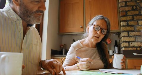 Engaged Mature Couple Discussing Household Finances at Kitchen Table