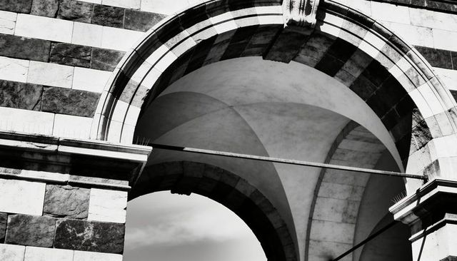 Monochrome romanesque arch with banded masonry, vaulted ceilings and weathered keystone detail