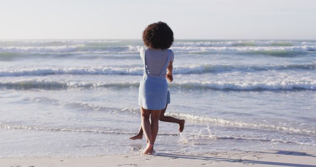 African american mother and her daughter playing on the beach. healthy outdoor leisure time by the sea.