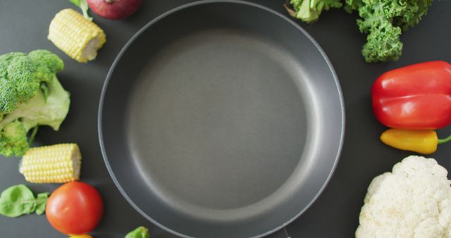 Image of fresh vegetables around frying pan with copy space on grey background. fusion food, fresh vegetables and healthy eating concept.