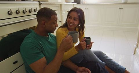 Happy couple relaxing on kitchen floor enjoying coffee