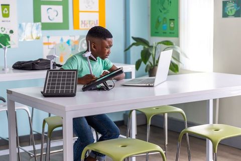 African american boy studying solar and wind energy with tablet and laptop in stem lab