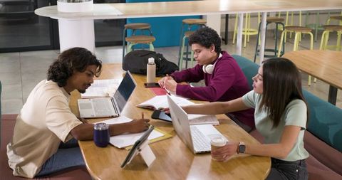 African American students studying in campus commons with laptops, notebooks and coffee