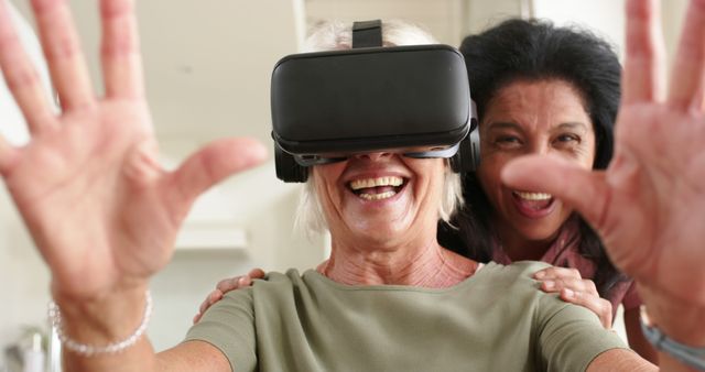 Two senior women engaging with virtual reality headset, showing joyful and expressive emotions. Great for illustrating elderly engagement with technology, fun activities for seniors, and digital interaction among older adults. Useful for tech products targeting senior markets, healthcare technology, and lifestyle content promoting active aging.