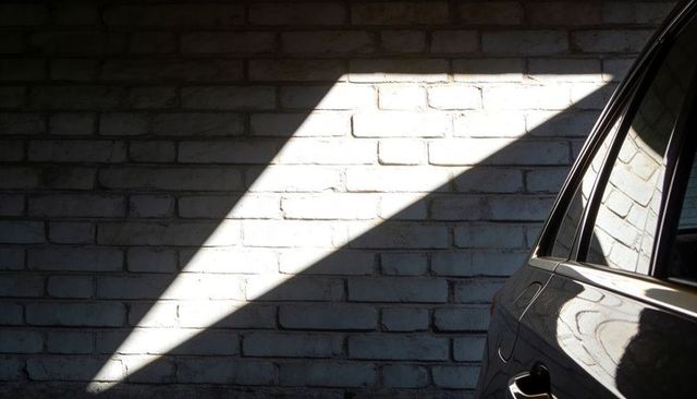 Sunbeam cutting across painted brick wall with glossy car reflection in garage