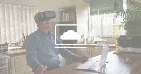Senior man wearing vr headset exploring cloud analytics while using laptop in kitchen
