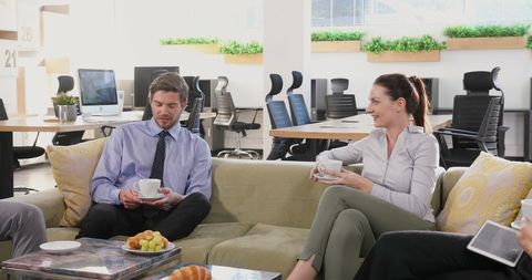 Professionals Engaging in Casual Conversation Over Coffee at Modern Office Lounge