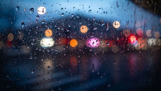 Rain-soaked window with soft bokeh city lights at dusk