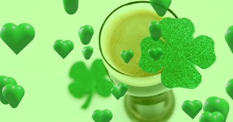 Floating glossy green hearts circling frothy emerald cocktail with glitter shamrock
