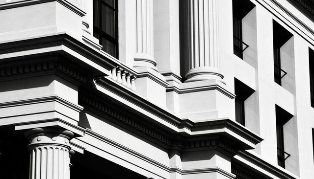 Neoclassical facade corner featuring fluted columns, dentil cornice and strong shadows