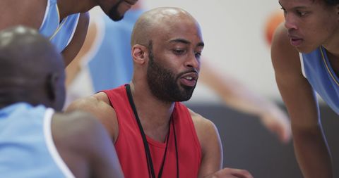 Basketball Coach Guiding Diverse Men's Team on Indoor Court