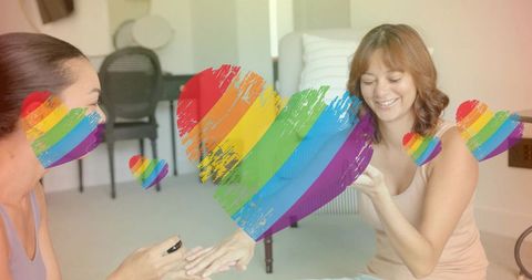 Friends sharing at-home manicure with rainbow pride hearts, cozy lgbtq+ bonding moment
