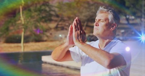 Serene Mature Man Meditating by Pool with Lens Flare