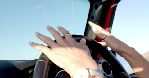 Female hands gripping steering wheel on sunny drive